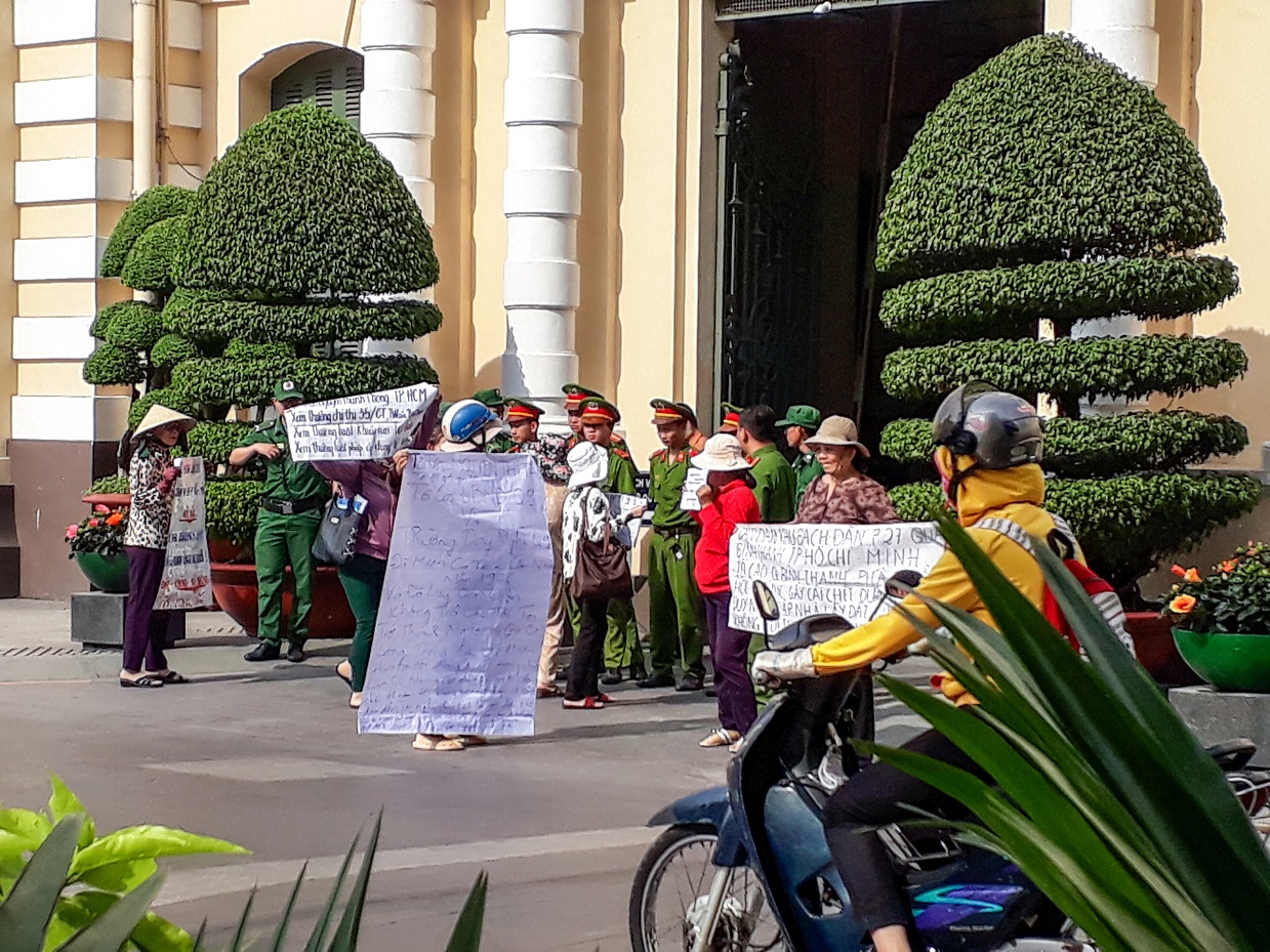 A group of Vietnamese women display banners outside the People’s Committee Building in Ho Chi Minh City on Jan 5, 2017. They are demanding redress for forced land seizure and police brutality. (Epoch Times)